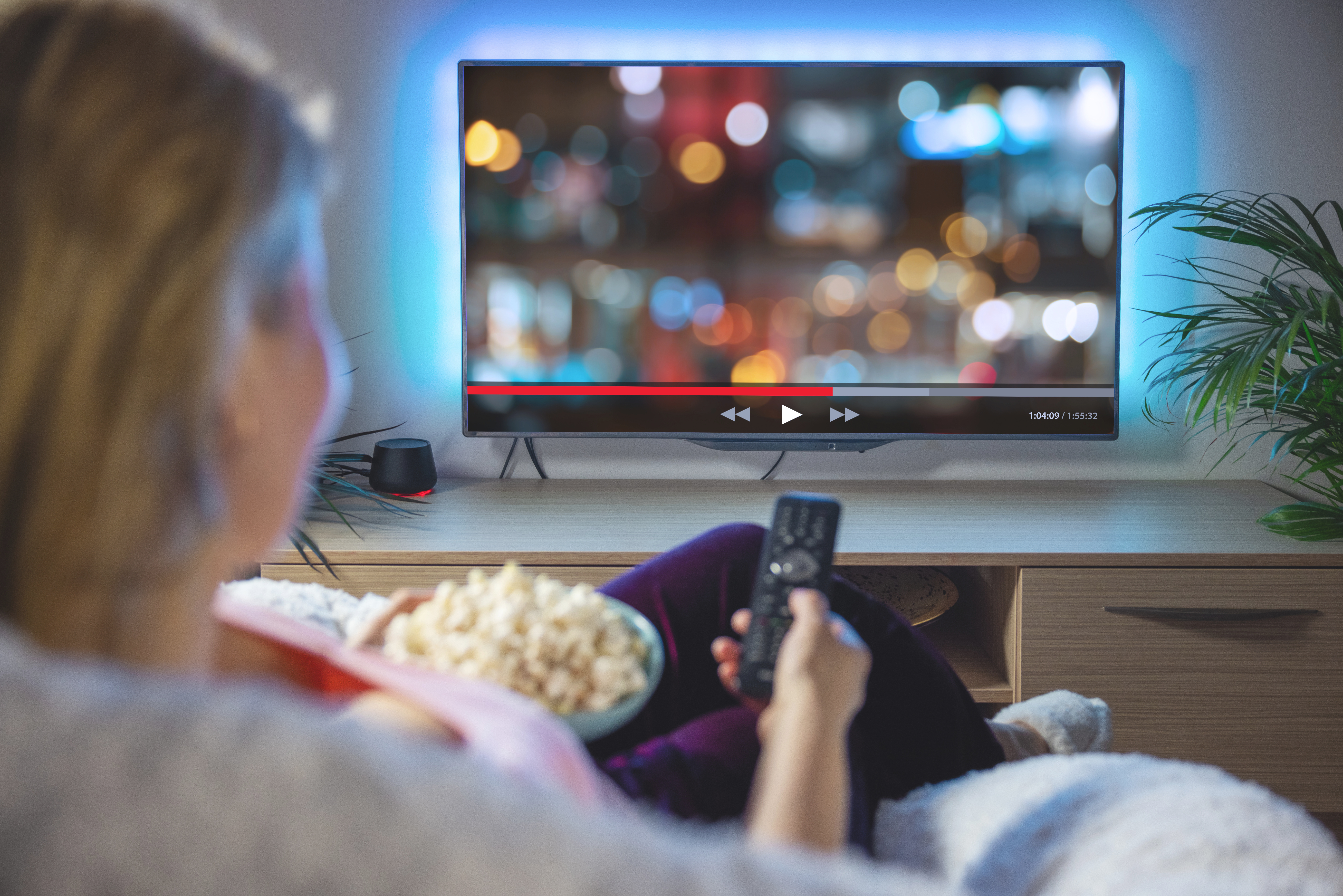 Eine Frau sitzt mit Popcorn vor dem Fernseher und streamt ein Video (Bildquelle:  Kaspars Grinvalds - stock.adobe.com)