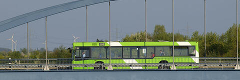 Ein öffentlicher Bus fährt über eine Brücke. Im Hintergrund sind Windräder zu sehen. (Quelle: Rolf Stumpf – Fotolia.com) Ein öffentlicher Bus fährt über eine Brücke. Im Hintergrund sind Windräder zu sehen. (Quelle: Rolf Stumpf – Fotolia.com)