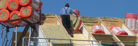 Ein Dach wird von Handwerkern mit einer dicken Schicht Steinwolle gedämmt (Quelle: Dr. Josef Hochhuber)