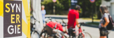 Plakat-Ankündigung eines Synergie-Festivals, Radfahrer im Hintergrund (Quelle: Energie-Atlas Bayern) Plakat-Ankündigung eines Synergie-Festivals, Radfahrer im Hintergrund (Quelle: Energie-Atlas Bayern)
