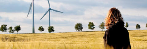 Eine Frau, die auf Windenergieanlagen blickt. (Quelle: Jens Ottoson - Fotolia.com)