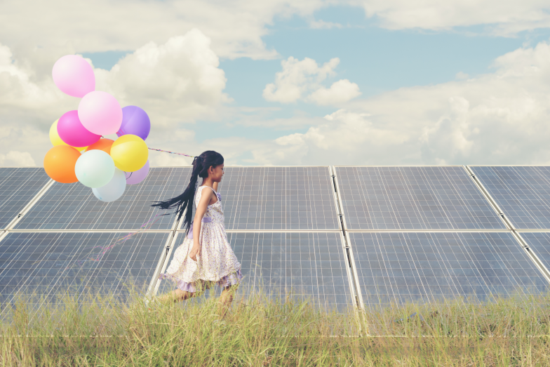 Ein Mädchen mit bunten Luftballons läuft vor einer Freiflächen-Photovoltaikanlage. Energiebildung für Kinder und Jugendliche ist sehr wichtig (Bildquelle: Palidachan - stock.adobe.com). Ein Mädchen mit bunten Luftballons läuft vor einer Freiflächen-Photovoltaikanlage. Energiebildung für Kinder und Jugendliche ist sehr wichtig.