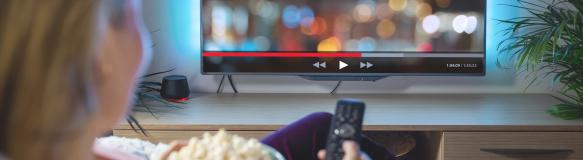 Eine Frau sitzt mit Popcorn vor dem Fernseher und streamt ein Video (Bildquelle: Kaspars Grinvalds - stock.adobe.com) Eine Frau sitzt mit Popcorn vor dem Fernseher und streamt ein Video (Bildquelle: Kaspars Grinvalds - stock.adobe.com)