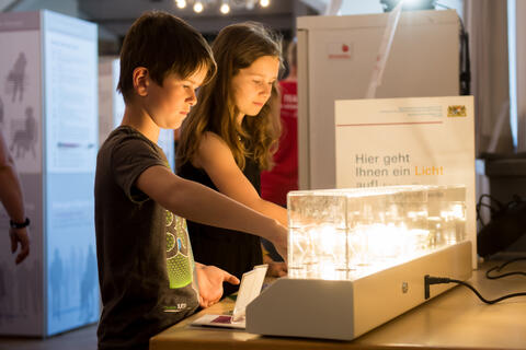 Kinder schauen sich verschiedene Leuchtmittel an - Eindruck von der Ausstellung Energiewende (Bildquelle: Tobias Hase)