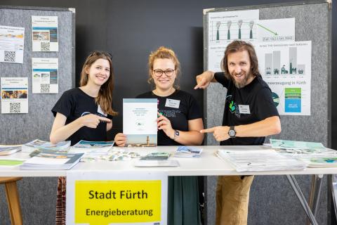 Drei Personen der Stadt Fürth stehen an ihrem Stand und präsentieren das Klimaschutzkonzept in gedruckter Form (Quelle: Daggi Binder, maizucker.de)