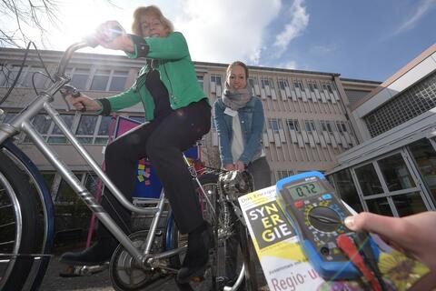 Zwei Frauen haben Spaß beim Stromerzeugen mit dem Fahrrad. Strom erzeugen mit dem Fahrrad ist ganz schön anstrengend. (Quelle: Stefan Puchner)