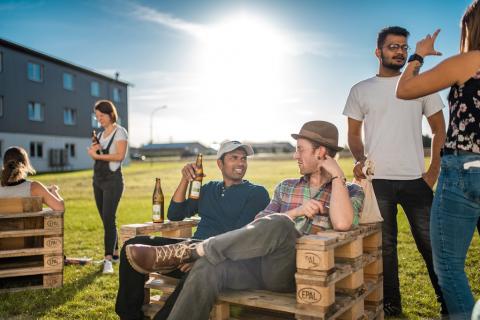 Entspannte Stimmung beim Synergie-Festival: Studenten, Akteure und Besucher sitzen auf Palettenmöbeln und stehen im Gespräch beieinander. (Quelle: LfU)