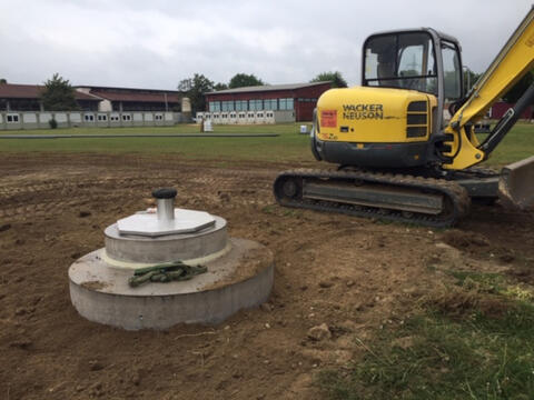 Brunnen Abschlussbauwerk mit einem Bagger daneben (Quelle: Simone Walker-Hertkorn)