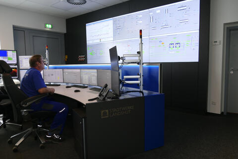 BMHKW Landshut, Innenaufnahme der neuen Leitzentrale; ein Mitarbeiter sitzt am Arbeitsplatz; Es sind Bildschirme und eine Informationswand zu erkennen (Quelle: Stadtwerke Landshut).