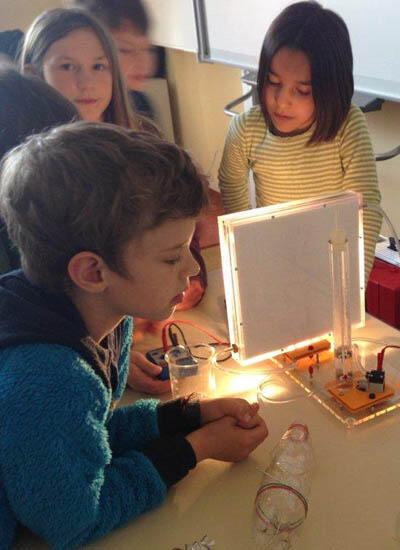 Die Kinder erwärmen mit einem Solarkollektor Wasser (Quelle: Energieagentur Regensburg e.V.)