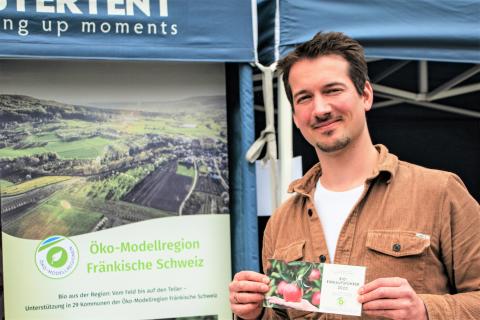 Ein junger Mann präsentiert den Bio-Einkaufsführer der Öko-Modellregion Fränkische Schweiz (Quelle: Oliver Kordes)