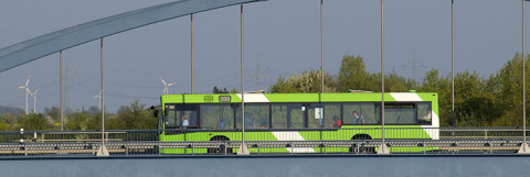 Ein öffentlicher Bus fährt über eine Brücke. Im Hintergrund sind Windräder zu sehen. (Quelle: Rolf Stumpf – Fotolia.com)