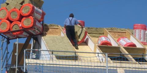 Ein Dach wird von einem Handwerker mit einer dicken Schicht Steinwolle gedämmt (Quelle: Dr. Josef Hochhuber)