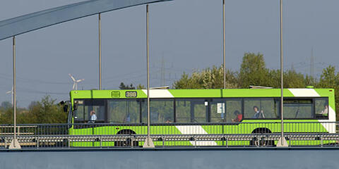 Ein öffentlicher Bus fährt über eine Brücke. Im Hintergrund sind Windräder zu sehen. (Quelle: Rolf Stumpf – Fotolia.com)