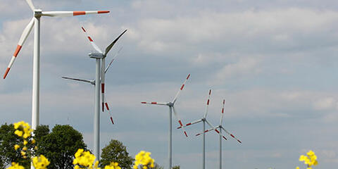 Mehrere Windenergieanlagen vor einem Rapsfeld. (Quelle: Uschi Dreiucker / PIXELIO)