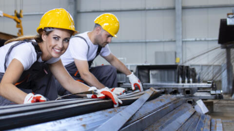 Das Bild zeigt zwei Beschäftigte in einem Betrieb in einer Produktionshalle (Bildquelle: littlewolf – stock.adobe.com).
