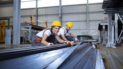 Das Bild zeigt zwei Beschäftigte in einem Betrieb in einer Produktionshalle (Bildquelle: littlewolf – stock.adobe.com).
